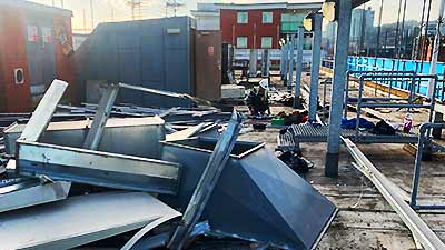 diagonal photo of a howarth site expert loading unwanted scrap metal items into the back of a white van with both back doors wide open and partially laden with scrap metal