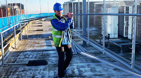 a howarth recycling site clearance specialist dressed in high visual clothing carrying metal bars just removed from a commercial site clearance and collection job on a sheffield commercial roof