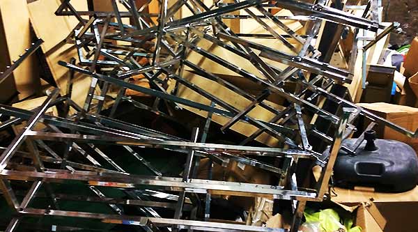 close up of a large amount of metal chromed shelving rails in a huge pile along with old metal stock including pallet racking and chrome fixtures and fittings