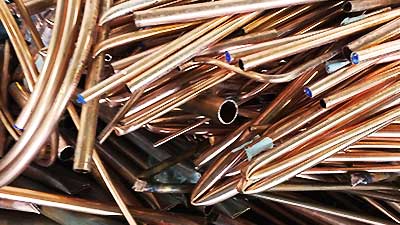 close up of a large amount of lovely super shiny scrap copper pipe in small lengths with some bent