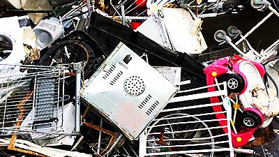 close up view of a large pile of typical sheffield scrap metal items from collections including childrens metal cars in red and white along with an old television tv and some old white metal gates