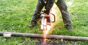 close up view of a howarth scrap metal expert dressed in high visibility clothing using a high speed cutting spinning disk tool to cut through some large too bulky to transport scrap metal girders left over from a home extension with sparks flying resembling a firework