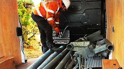 close up photo of our scrap companies expert dismanltling and loading a white van with commercial scrap piping from a factory demolition