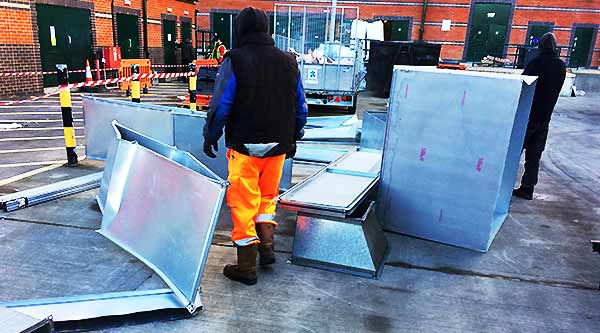 close up of two howarth office clearing experts carefully dismantling and loading several large metal office fixtures and fittings onto our office flat back truck